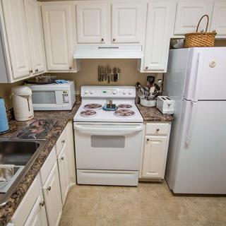 A compact kitchen with white appliances and cabinets.
