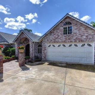 A suburban brick house with a garage and driveway under a blue sky.