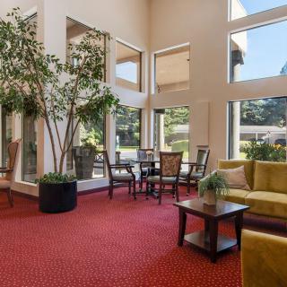 A spacious lobby with large windows, featuring comfortable seating and indoor plants.