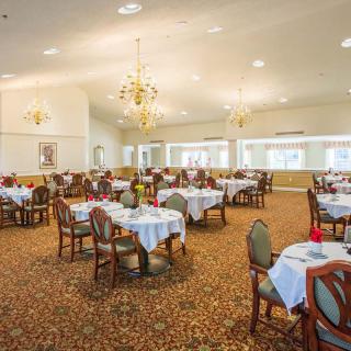 An elegant dining room with neatly arranged tables and chandeliers.