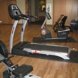 A gym room with various exercise equipment including a treadmill and stationary bikes.