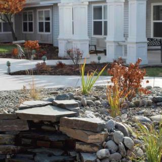 A beautifully landscaped yard with rocks and plants in front of a house.