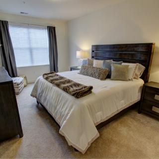 A cozy bedroom with a large bed, dark wooden furniture, and soft lighting.