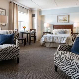A well-furnished bedroom featuring a bed, patterned chairs, and elegant decor.
