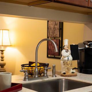 A cozy kitchen space with a sink, lamp, and coffee maker on the countertop.