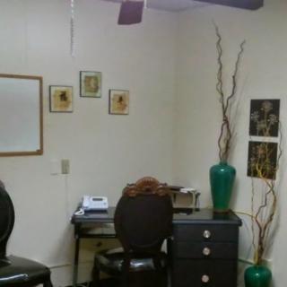 A small office space featuring a desk, chair, and decorative vases.