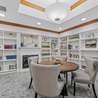A cozy reading nook featuring a circular dining table surrounded by soft chairs and shelves filled with books.