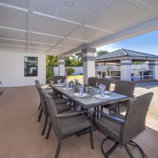 An elegant outdoor dining area with a modern table setting under a covered patio.