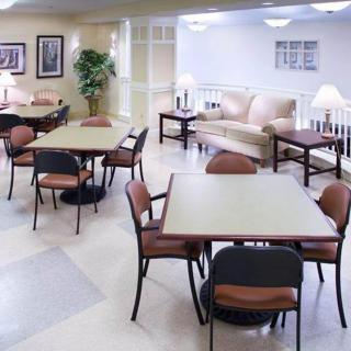 A comfortable lounge area with tables and chairs, well-lit by lamps.