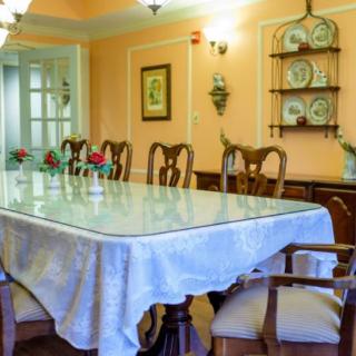 A well-decorated dining room featuring a long table with a white tablecloth, surrounded by wooden chairs.