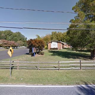 A quiet residential neighborhood featuring a house surrounded by trees and a well-maintained lawn.