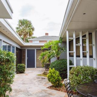 A charming courtyard featuring lush greenery and a patio area within a modern architectural setting.