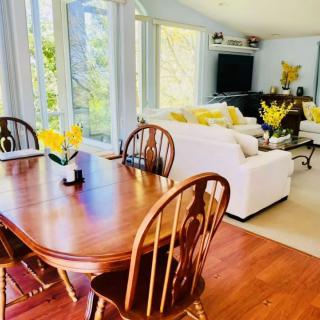 A bright and airy open-concept living and dining area with a wooden table, white sofas, and touches of yellow decor.