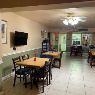 A cozy dining area with tables, chairs, and a television on the wall.