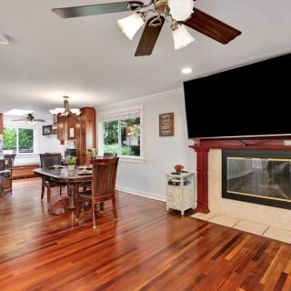 A cozy living and dining space featuring hardwood floors, a fireplace, ceiling fan, and an elegant dining area.