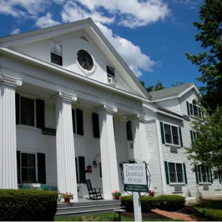 A classic architectural building featuring tall columns and a white facade, set against a backdrop of fluffy clouds.