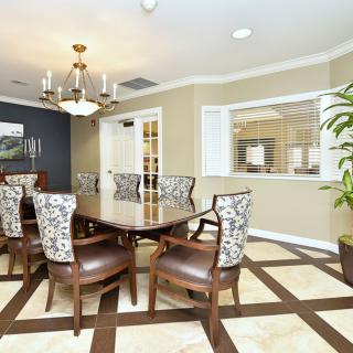 A modern dining room with a large wooden table, upholstered chairs, and a stylish chandelier.