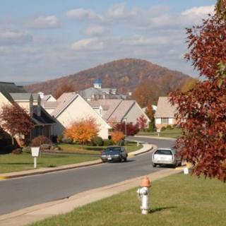 A picturesque suburban neighborhood with colorful autumn foliage and a mountain in the background.