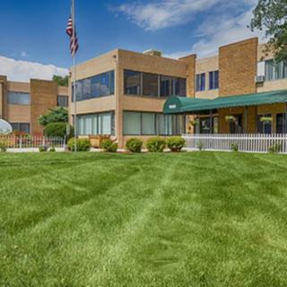 A brick building with a manicured lawn and an American flag flying on a pole.