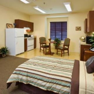 A cozy studio apartment featuring a combined bedroom and kitchen area with a small dining table.