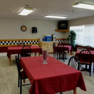 An empty restaurant dining area with tables covered in red tablecloths.