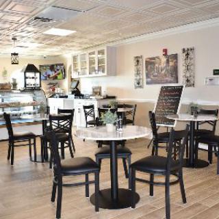 A bright and modern cafe interior with tables and chairs arranged neatly, and a counter in the background.