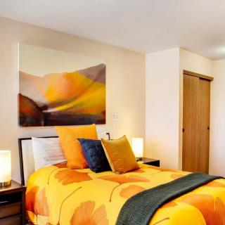 A modern bedroom with orange bedding and artistic wall decor.