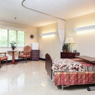 A well-lit and clean hospital patient room equipped with a bed, seating area, and window.
