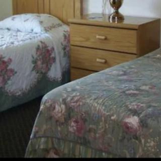 A cozy bedroom with two beds adorned with floral bedspreads and a wooden nightstand with a lamp.