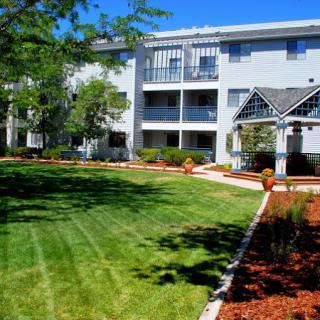 A well-maintained apartment complex with a lush green lawn and landscaped gardens.
