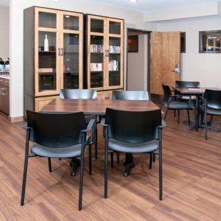 A cozy indoor dining area with tables, chairs, and a wooden cabinet.