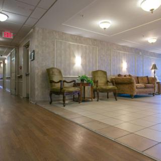 A well-lit hallway with a seating area, featuring comfortable chairs and decorative lights.