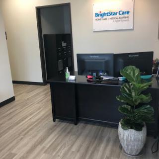 A clean and modern reception area of BrightStar Care with a workstation and indoor plant.