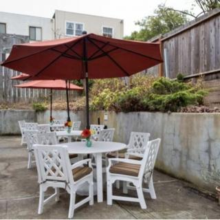A patio area with white furniture and red umbrellas in a backyard setting.