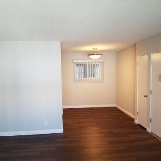 A bright and spacious living area with wood flooring and a neutral color scheme.