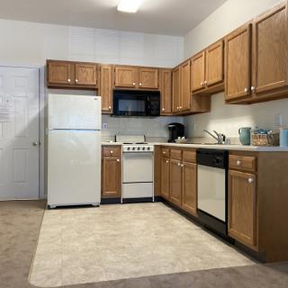 A modern kitchen with wooden cabinets, a refrigerator, stove, microwave, and dishwasher.