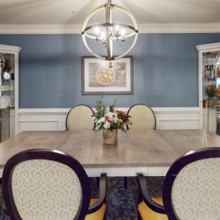A well-decorated dining room featuring a central table, upholstered chairs, and a modern chandelier.