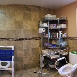 A well-equipped bathroom featuring medical assistive devices and organized storage shelves.
