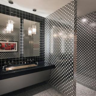 A modern bathroom with black and white mosaic tiles, featuring a sleek sink and elegant lighting.