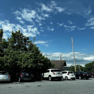 A view of a parking lot with various cars under a partly cloudy sky.