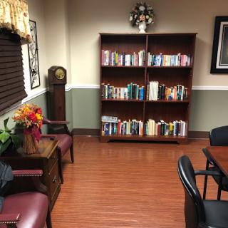 A cozy reading nook featuring a bookshelf filled with books, comfortable seating, and warm lighting.