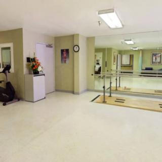 A clean and organized rehabilitation exercise room equipped with parallel bars and mirrors.