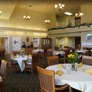 A well-lit dining area with neatly arranged tables and chairs, featuring elegant decor.