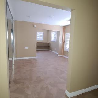 A spacious empty room with carpet flooring and several windows providing natural light.