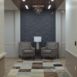 A modern waiting area with two chairs, a central lamp, and a chandelier.