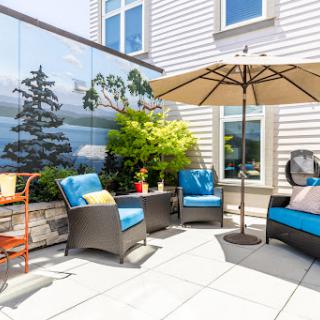 A stylish outdoor patio with comfortable seating, an umbrella for shade, and beautiful greenery.