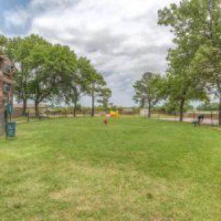 A scenic view of a grassy park area with trees and a playground in the background.