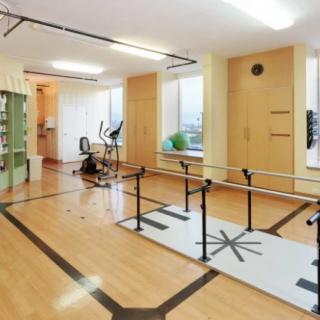 A well-equipped physical therapy room with parallel bars and exercise machines.