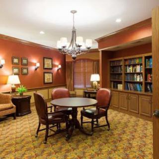 A cozy reading area featuring comfortable seating, a table for collaboration, and shelves filled with books.