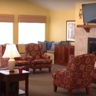A cozy living room with patterned armchairs, a fireplace, and a television.